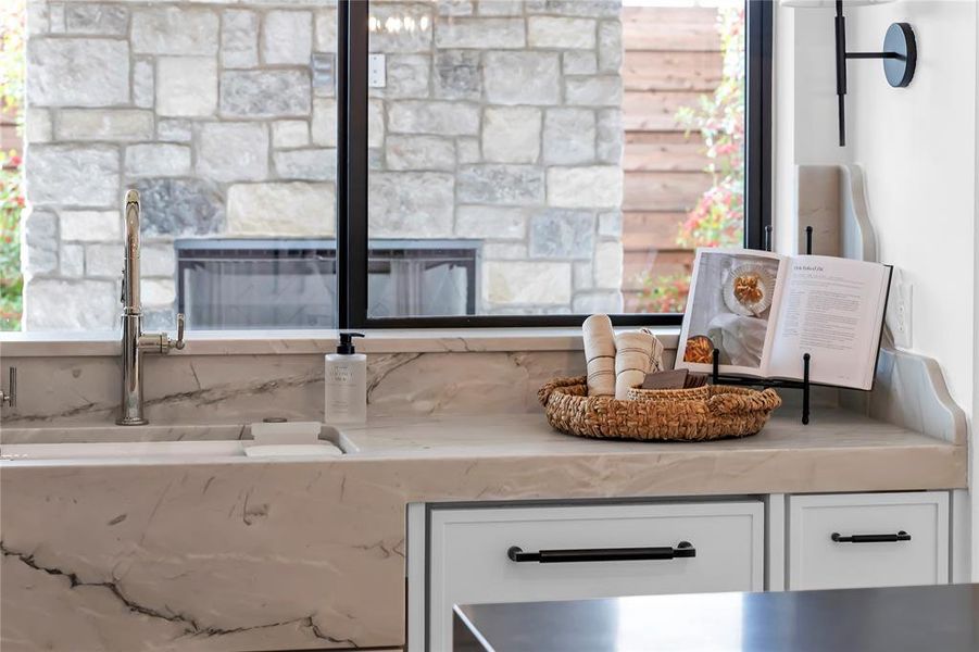 Kitchen view of white cabinets, light stone countertops, and a glass covered fireplace Kitchen view of white cabinets, light stone countertops, and a glass covered fireplace