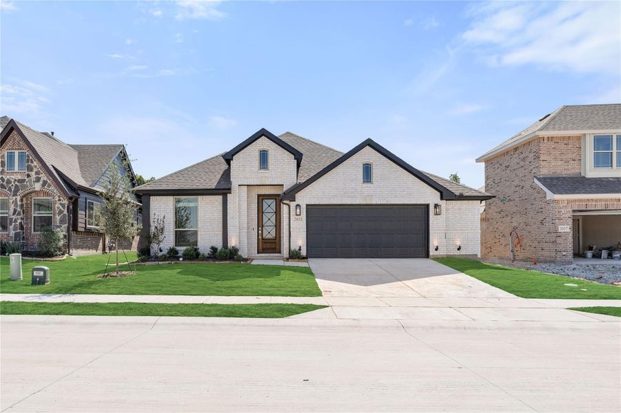 Single-story home with white brick exterior, dark trim, two-car garage, and green front lawn Single-story home with white brick exterior, dark trim, two-car garage, and green front lawn