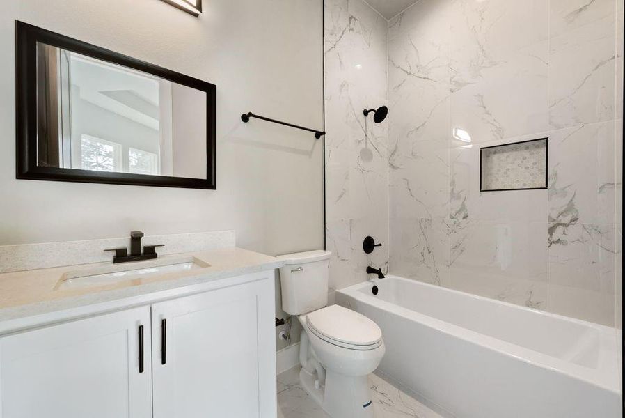 Full bathroom featuring toilet, vanity, and tiled shower / bath