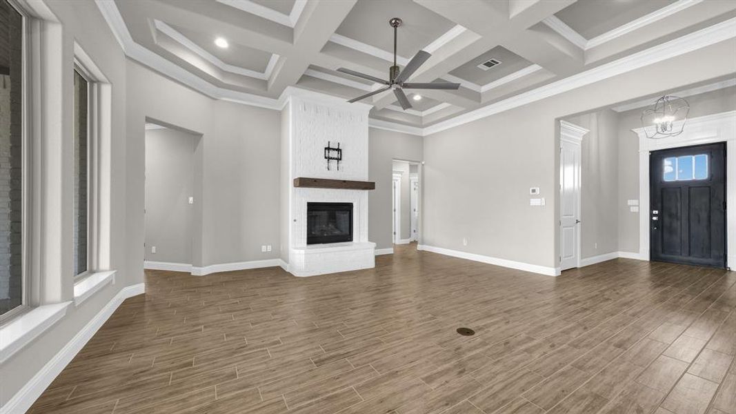 Living room featuring coffered ceiling, hardwood / wood-style floors, and a brick fireplace