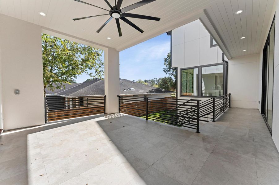 This photo showcases a spacious, covered patio with modern railings and a ceiling fan. perfect for outdoor relaxation.