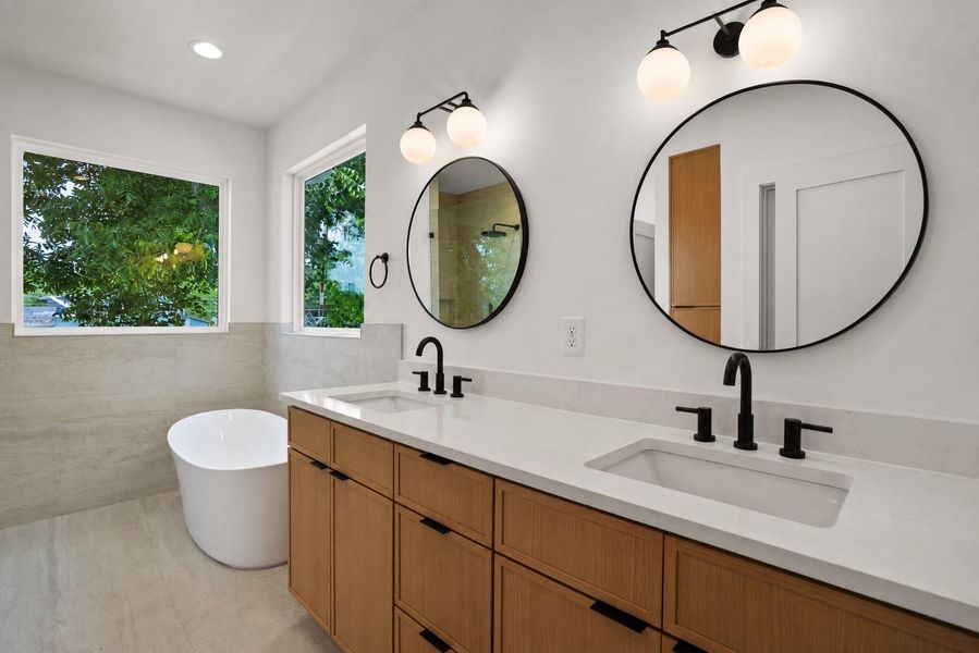Modern primary bathroom featuring dual vanities, freestanding tub, and elegant fixtures.