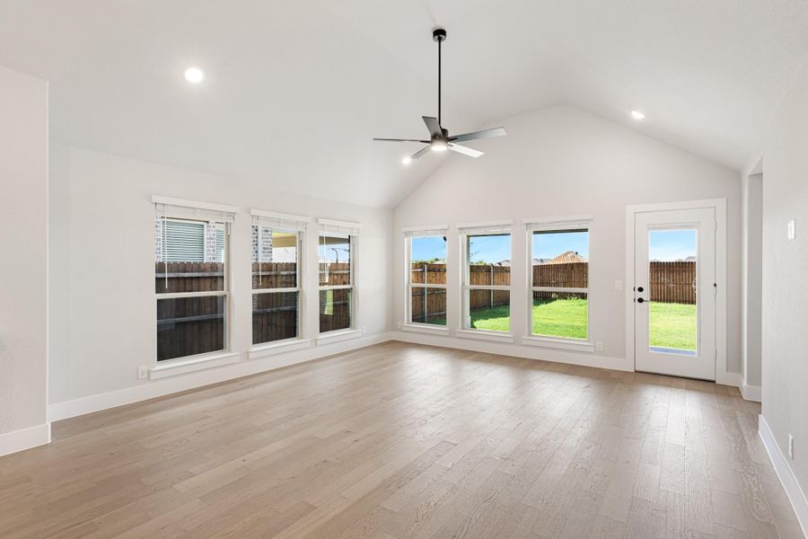 Open living area with vaulted ceiling, ceiling fan, hardwood floors, and back door with backyard views Open living area with vaulted ceiling, ceiling fan, hardwood floors, and back door with backyard views