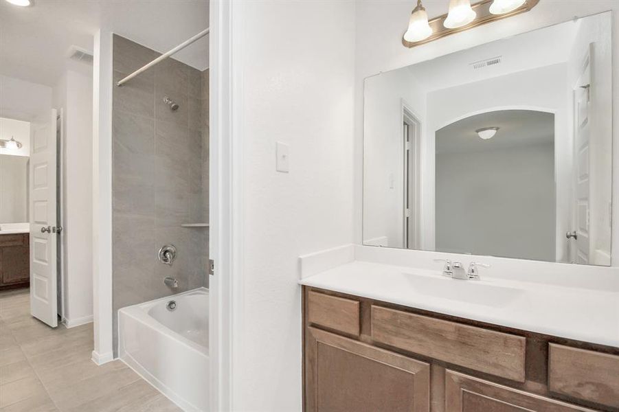 Secondary bathroom features a tub and shower combo with tile surround.