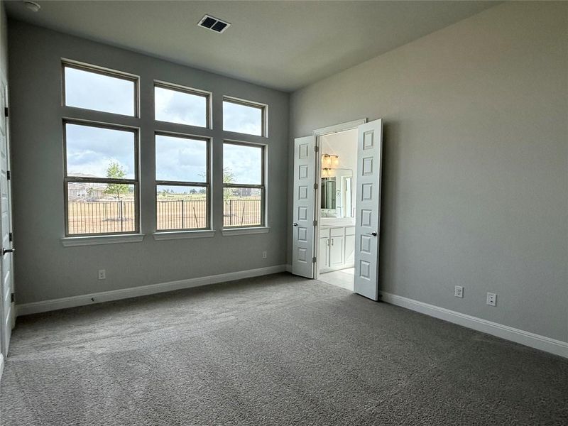 Unfurnished bedroom featuring multiple windows, carpet flooring, and ensuite bath Unfurnished bedroom featuring multiple windows, carpet flooring, and ensuite bath