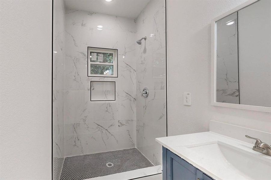 Primary bathroom with tiled shower and vanity