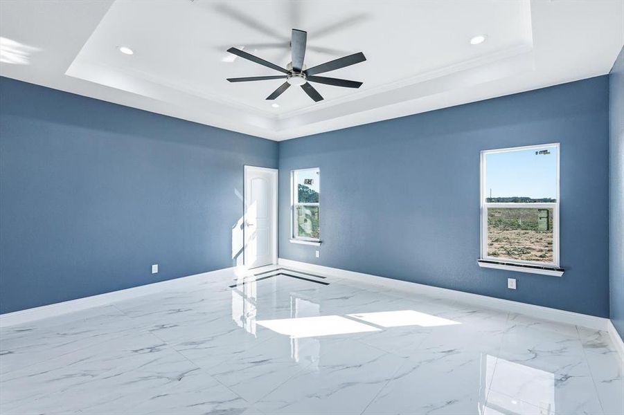 Spare room with a tray ceiling, marble look tiles, recessed lighting, ornamental molding, and ceiling fan