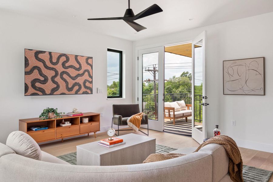 Living area with healthy amount of natural light, light wood finished floors, and a ceiling fan Living area with healthy amount of natural light, light wood finished floors, and a ceiling fan