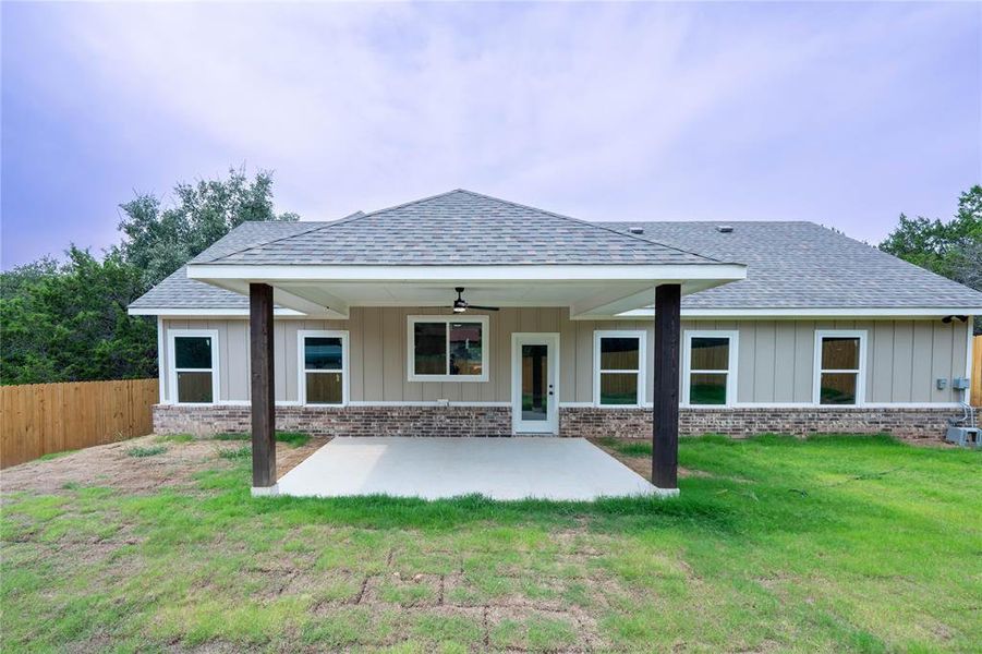 Back of property with ceiling fan, a patio area, and a yard