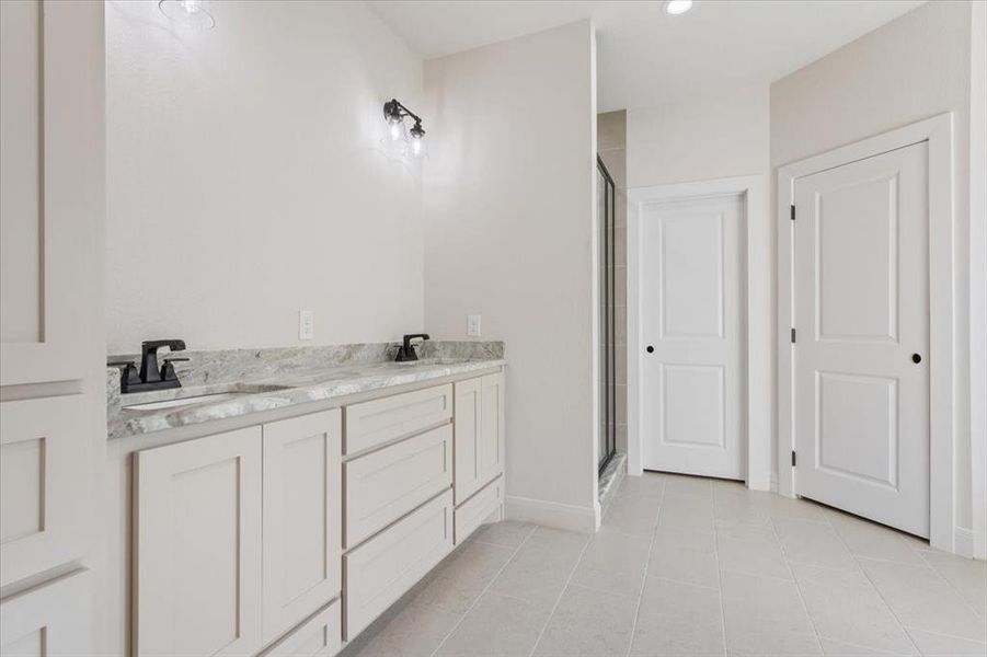 Full bath featuring double vanity, a stall shower, light tile patterned flooring, and recessed lighting