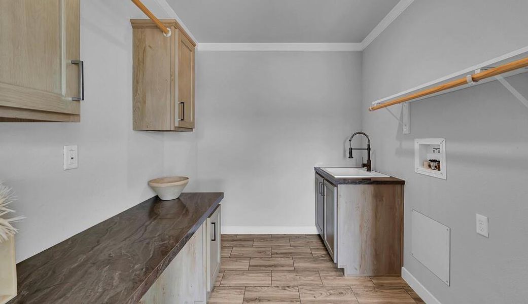 Laundry room with wood tiled floors, cabinet space, washer hookup, and ornamental molding Laundry room with wood tiled floors, cabinet space, washer hookup, and ornamental molding
