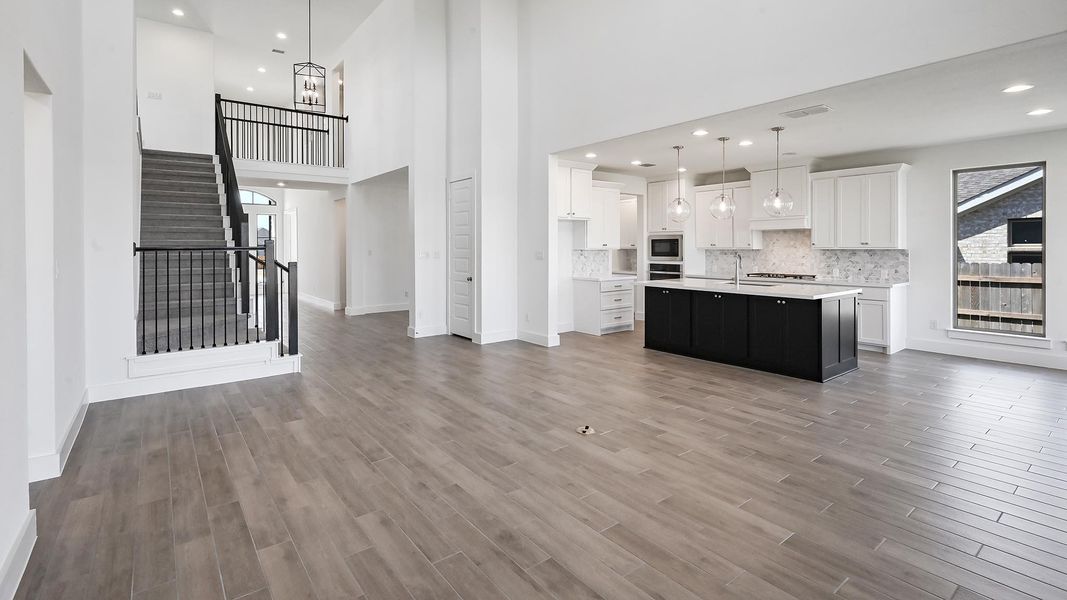 Kitchen featuring recessed lighting, light countertops, open floor plan, white cabinetry, and wood finished floors