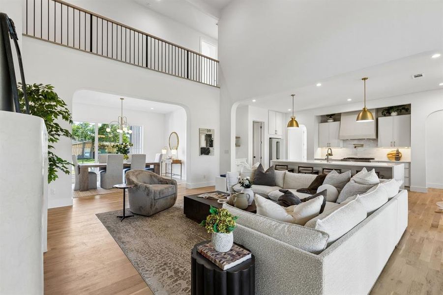 Living room with arched walkways, a high ceiling, hanging lights, and light wood-type flooring