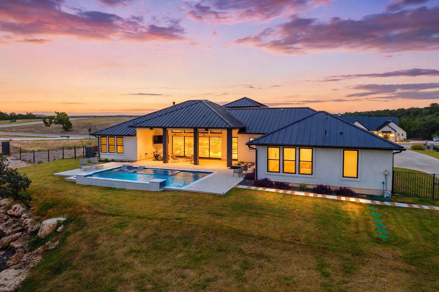Clean lines and a striking metal roof define this modern architectural estate at sunset.
