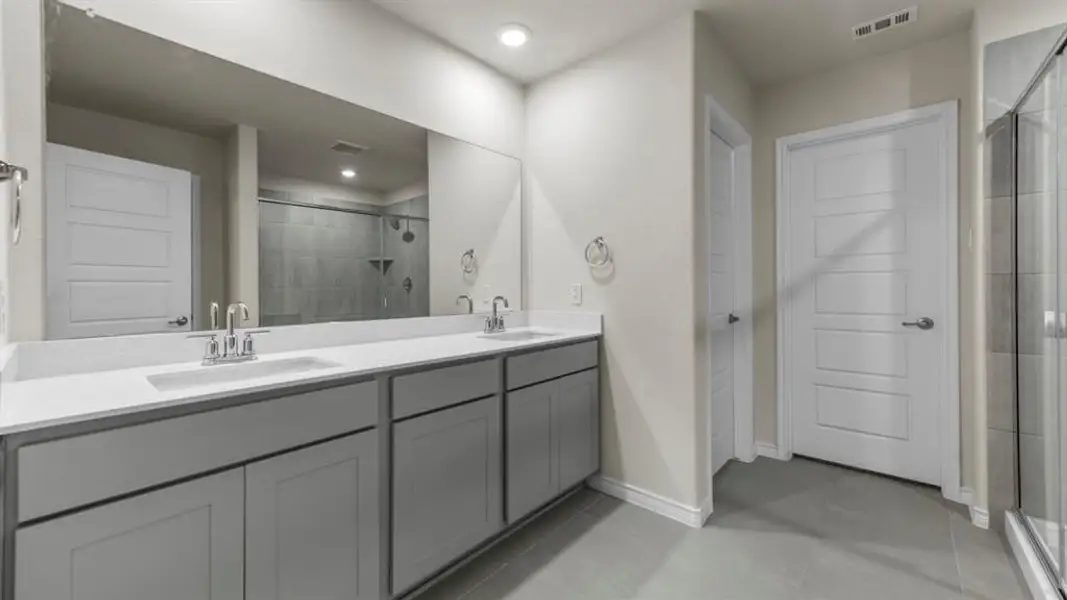 Bathroom featuring a dual vanity with light gray cabinetry and white countertops