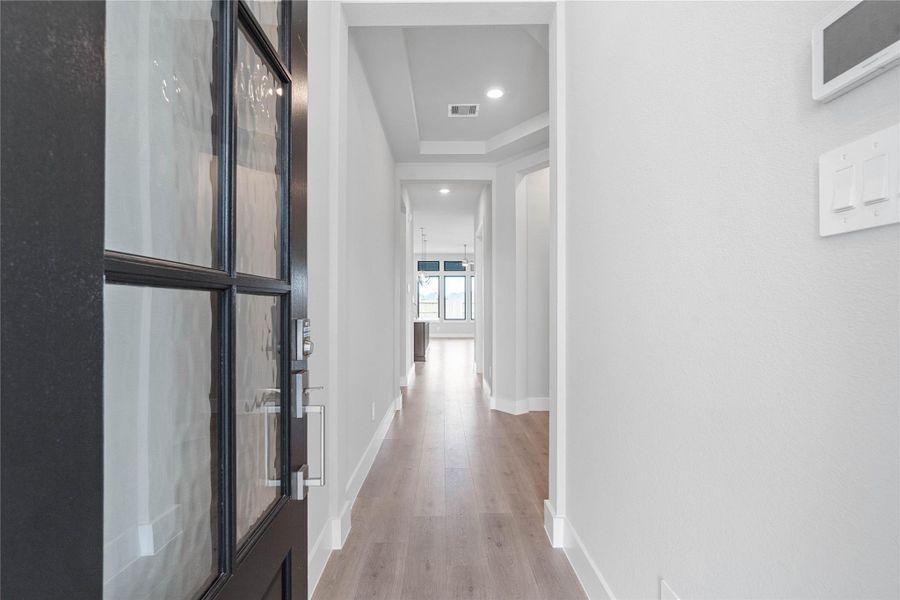 Welcome inside to a bright and inviting entryway that sets the tone for this modern home. Crisp white walls and abundant natural light create an open and spacious feel throughout the hallway. The laminate flooring extends seamlessly through the area, offering both aesthetic appeal and durability.