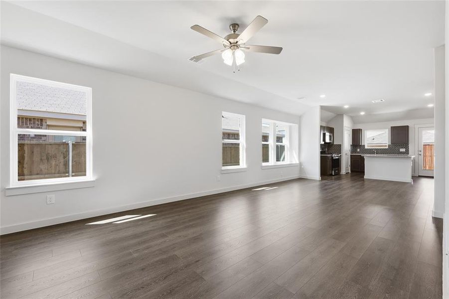 Unfurnished living room with a ceiling fan, plenty of natural light, dark wood-type flooring, and recessed lighting
