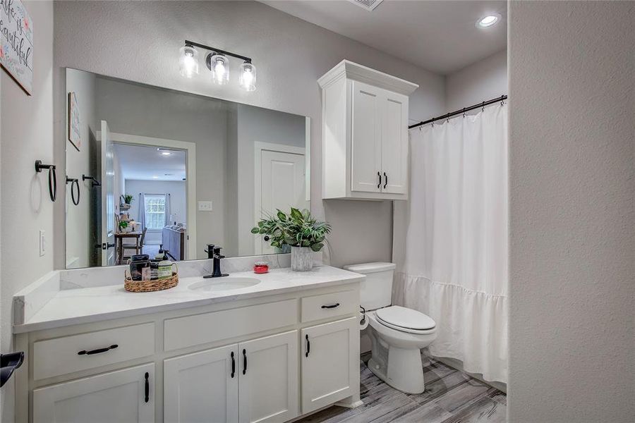 Bathroom with hardwood / wood-style floors, vanity, curtained shower, and toilet