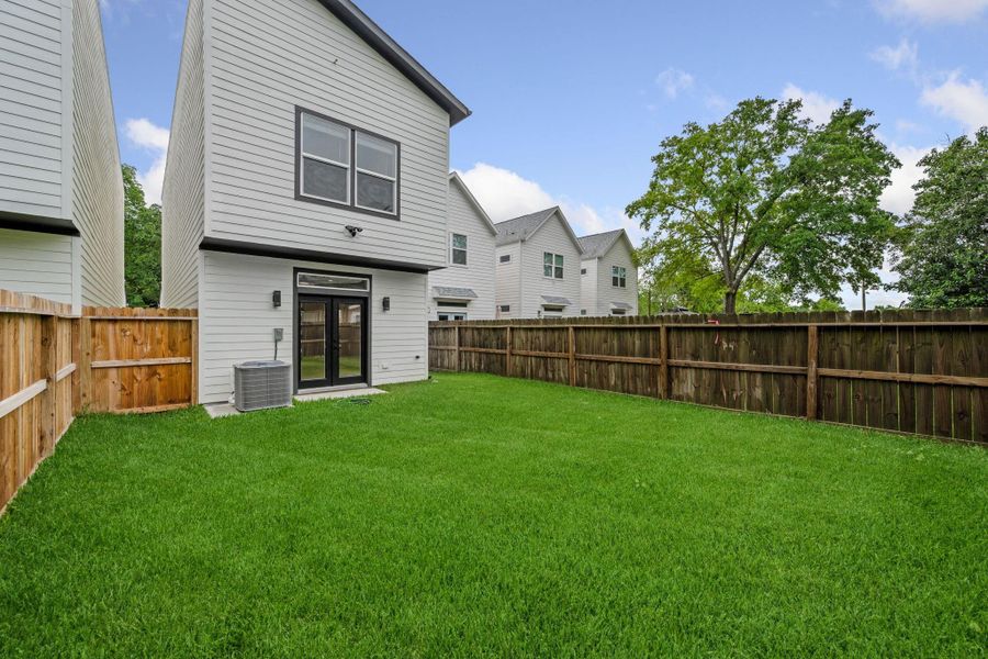 Spacious fenced backyard with lush green grass, perfect for outdoor activities and privacy.