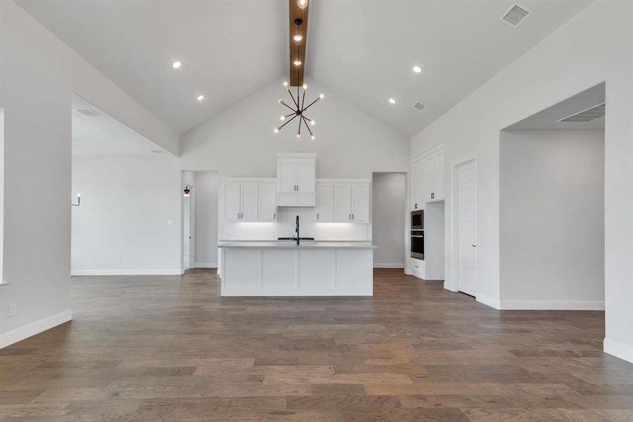 Kitchen featuring beam ceiling, hardwood / wood-style floors, a center island with sink, and high vaulted ceiling