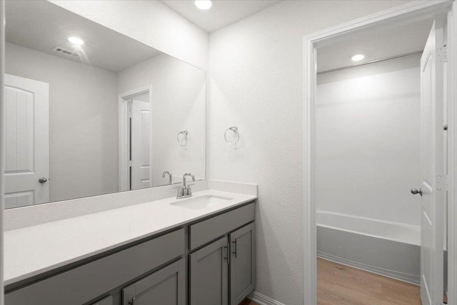 Bathroom featuring a single vanity with grey cabinetry, a white countertop, and a rectangular undermount sink with a chrome faucet