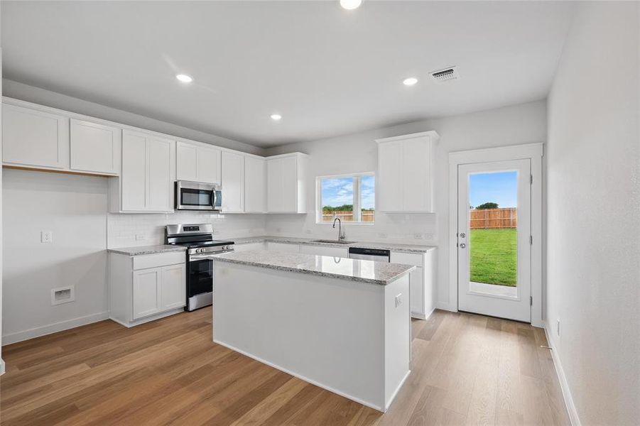 Kitchen with appliances with stainless steel finishes, a sink, decorative backsplash, white cabinets, and recessed lighting Kitchen with appliances with stainless steel finishes, a sink, decorative backsplash, white cabinets, and recessed lighting