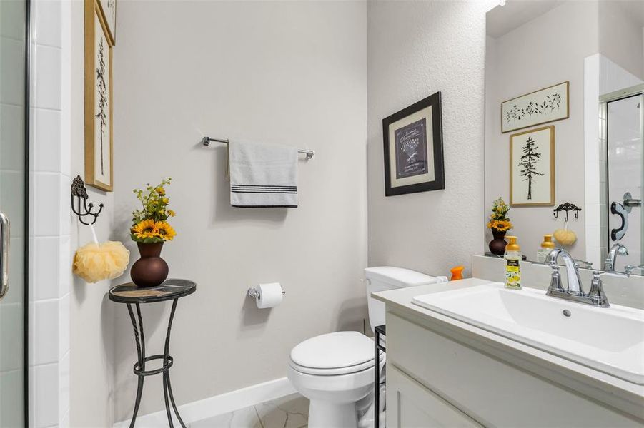 Bathroom featuring a shower with door, vanity, and toilet