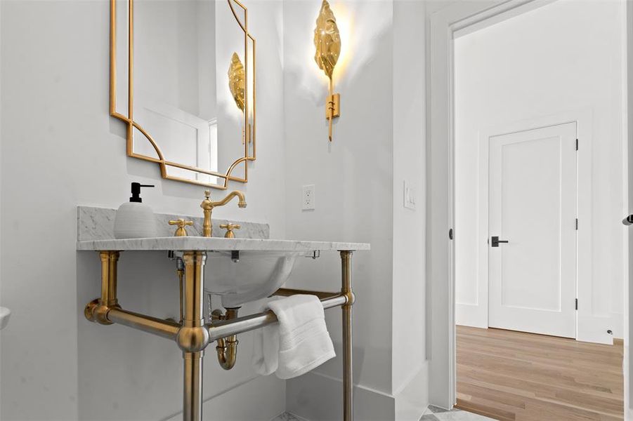 Formal powder bath with tumbled white and gray pattern marble floor and brass freestanding vanity