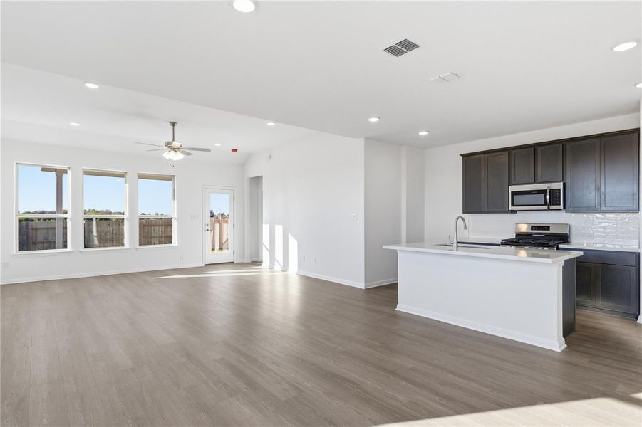 Kitchen featuring a center island with sink, open floor plan, recessed lighting, stainless steel appliances, and light wood finished floors