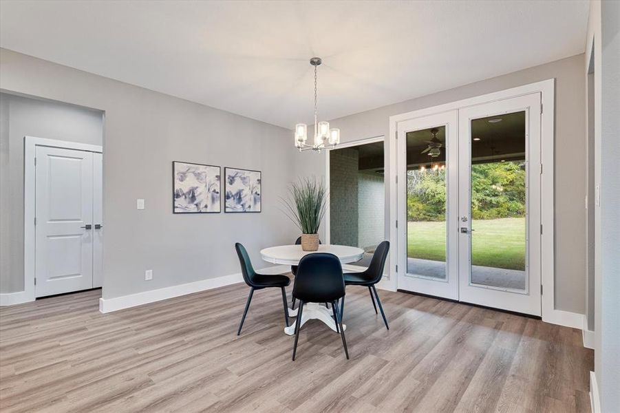 Dining space featuring light wood-type flooring, an inviting chandelier, and french doors Dining space featuring light wood-type flooring, an inviting chandelier, and french doors