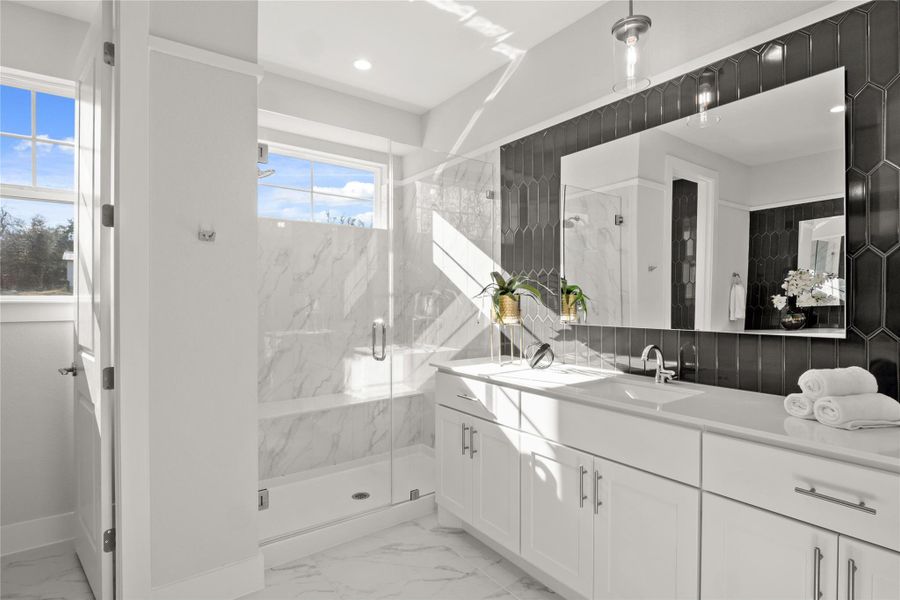 Full bath featuring marble look tile flooring, double vanity, and a marble finish shower Full bath featuring marble look tile flooring, double vanity, and a marble finish shower