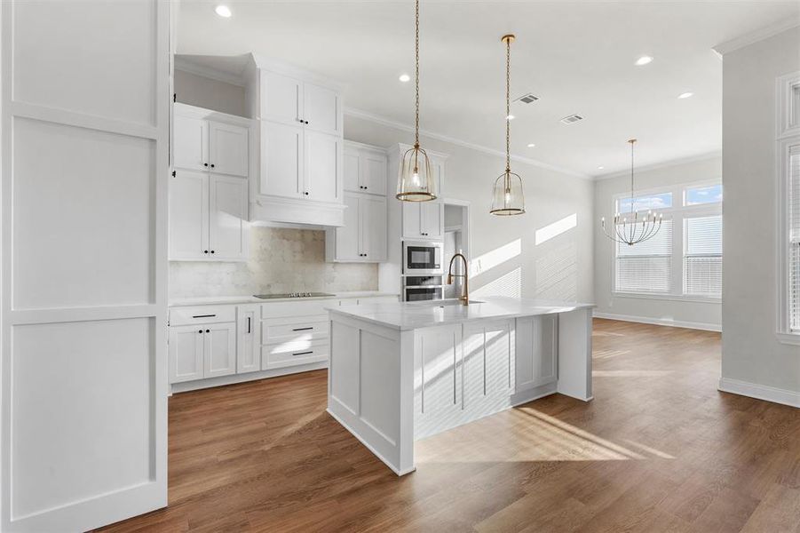 Kitchen featuring decorative backsplash, ornamental molding, white cabinetry, light stone countertops, and hanging light fixtures Kitchen featuring decorative backsplash, ornamental molding, white cabinetry, light stone countertops, and hanging light fixtures