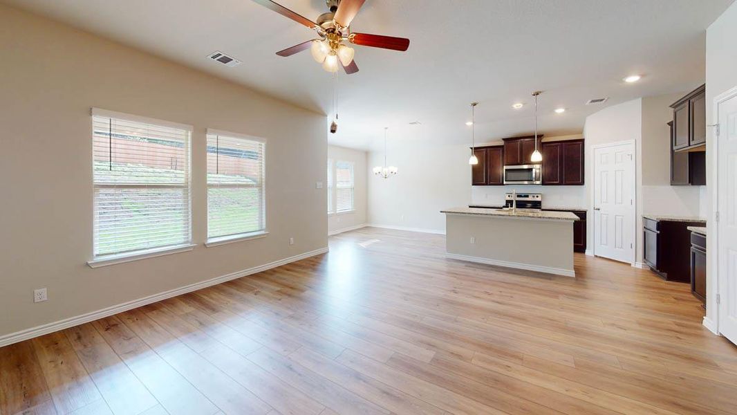 Kitchen with a chandelier, open floor plan, a center island with sink, a ceiling fan, and dark wood finish cabinets