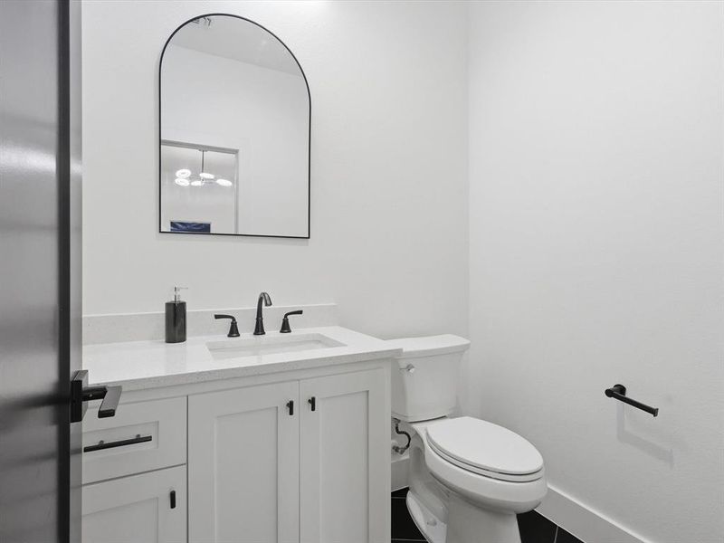 Bathroom on second level, featuring white shaker-style cabinetry, a white countertop with an integrated sink, matte black faucet, and an arched mirror