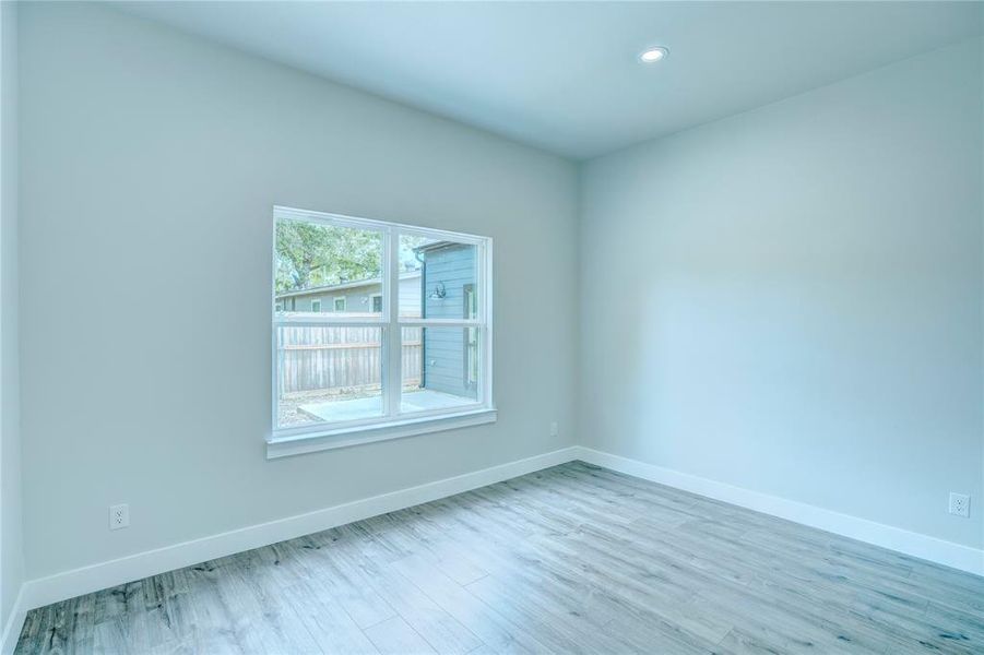 Interior space featuring light-toned walls, wood-finish flooring, recessed lighting, and a white-framed window