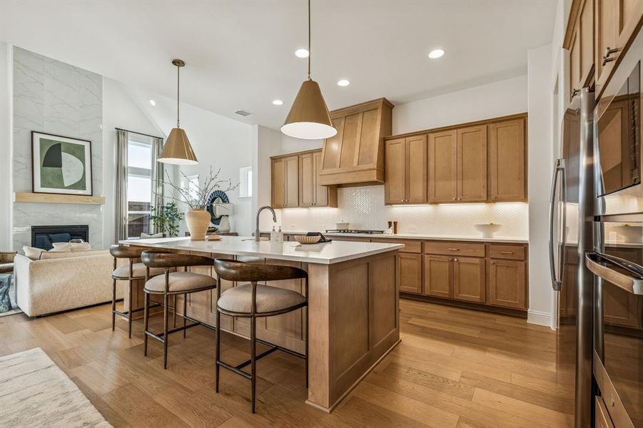 Kitchen with lofted ceiling, a breakfast bar, light wood-style floors, a large fireplace, and wood finish cabinets