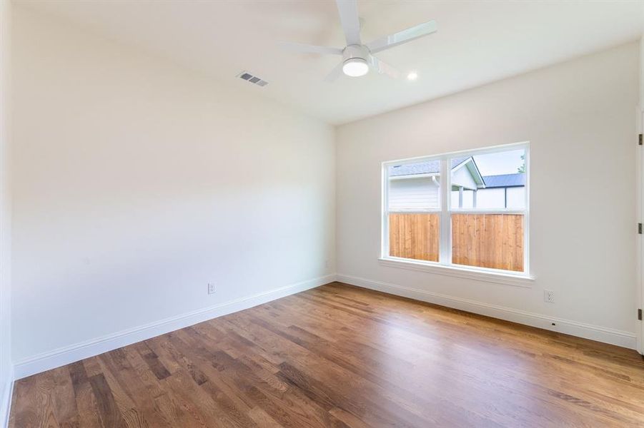 Hardwood flooring, white baseboards, a white ceiling fan with integrated lighting, a recessed ceiling light, and a window with white trim Hardwood flooring, white baseboards, a white ceiling fan with integrated lighting, a recessed ceiling light, and a window with white trim