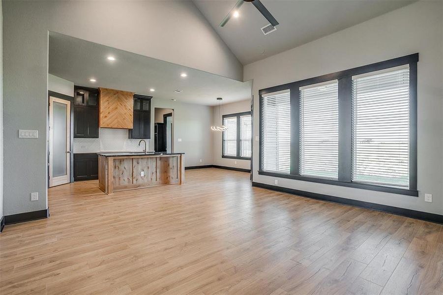 Kitchen featuring tasteful backsplash, ceiling fan, sink, light hardwood / wood-style floors, and an island with sink