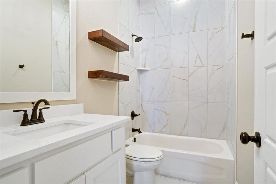 Full bathroom featuring tile patterned flooring, tiled shower / bath combo, toilet, and vanity