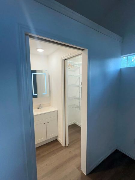 A well-appointed vanity with integrated lighting sits opposite a spacious walk-in closet, maximizing utility.