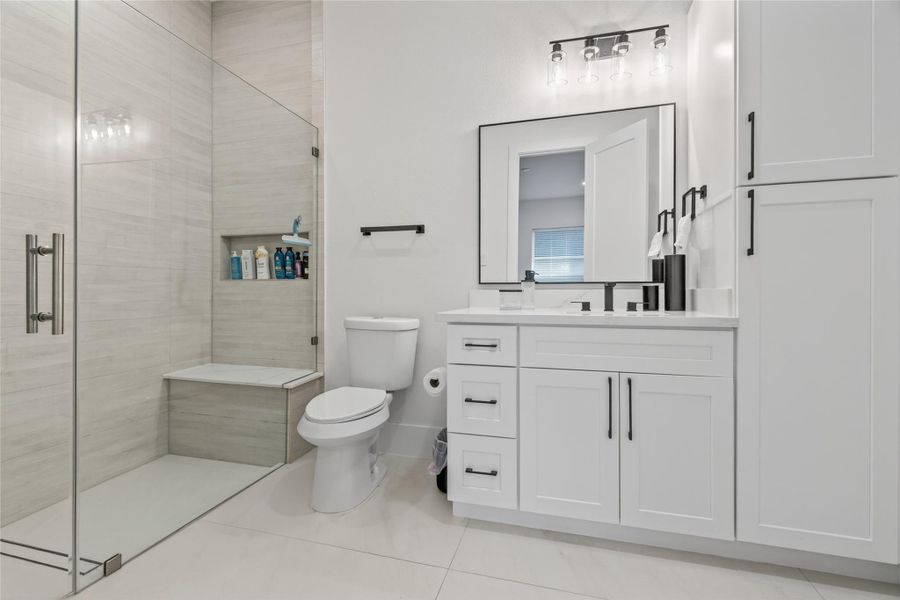 Full secondary bathroom includes a glass-enclosed shower, modern vanity, and crisp contemporary finishes. **Images are from a previously completed project. **