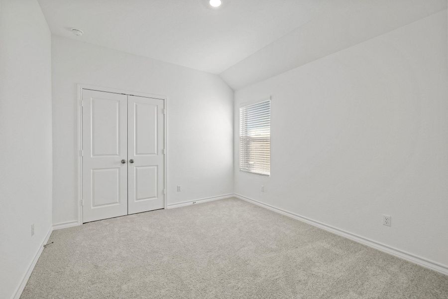 Unfurnished bedroom with carpet, a closet, and vaulted ceiling