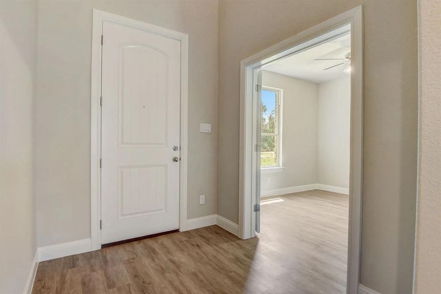 Foyer entrance with wood finished floors, ceiling fan, and baseboards