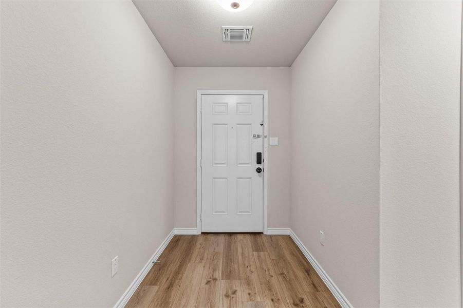 Doorway with baseboards and wood finished floors