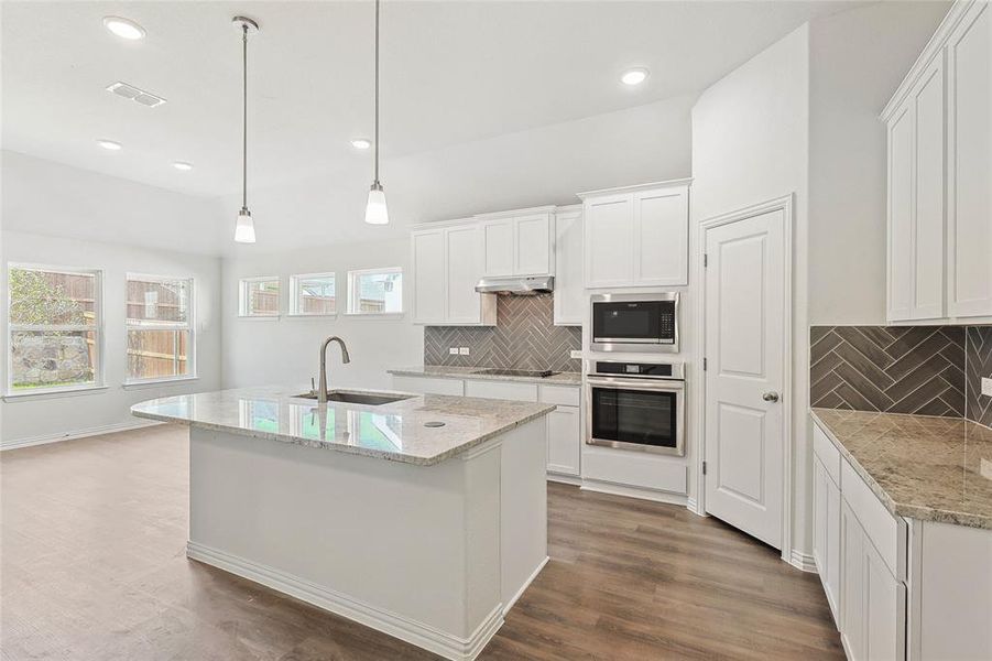 Kitchen featuring appliances with stainless steel finishes, hardwood / wood-style floors, wall chimney range hood, sink, and decorative backsplash