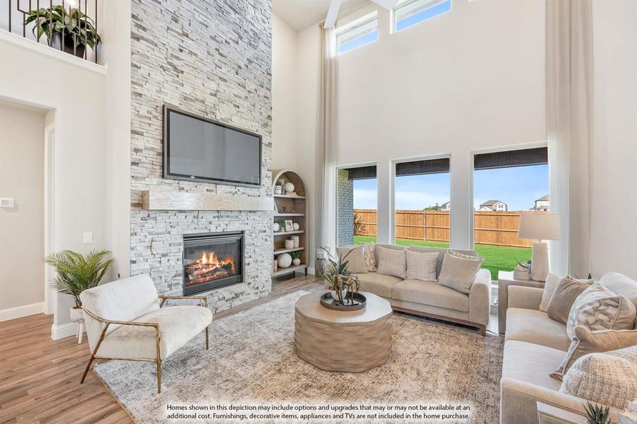 Living room with two-story stone fireplace, wall-mounted TV, and large windows overlooking backyard Living room with two-story stone fireplace, wall-mounted TV, and large windows overlooking backyard