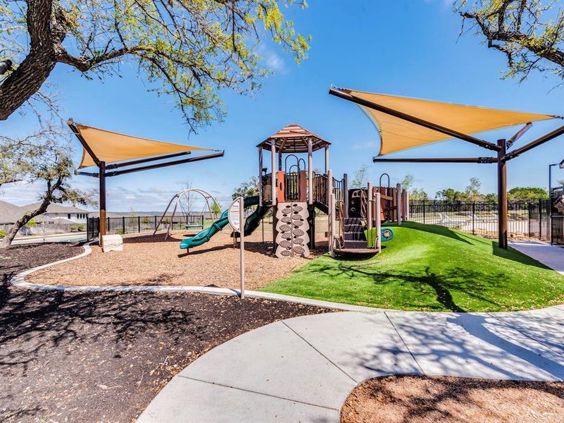 A vibrant playground features shade structures, slides, and swings, inviting outdoor activity.