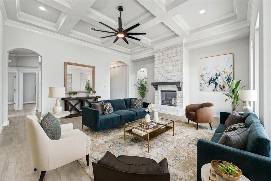 Living area with arched walkways, a ceiling fan, wood finished floors, a fireplace, and beam ceiling