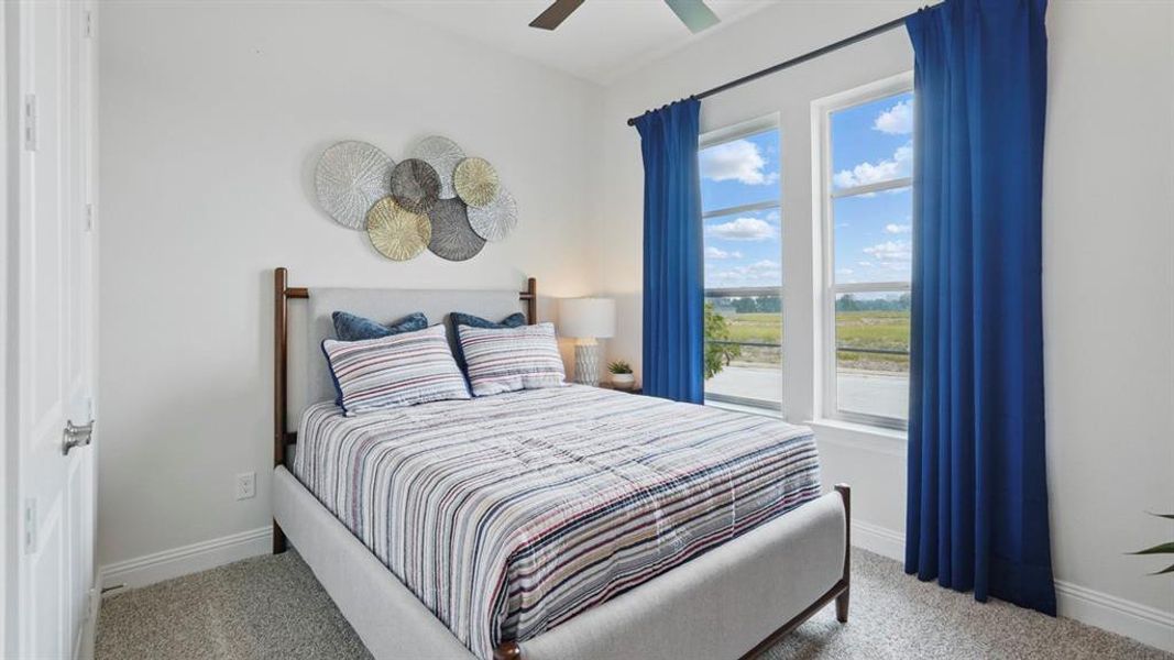 Bright room featuring two large windows, white walls, gray carpeting, a multi-paneled door, and a ceiling fan