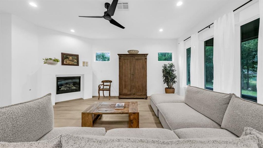 Living room featuring recessed lighting, light wood-type flooring, a glass covered fireplace, and ceiling fan Living room featuring recessed lighting, light wood-type flooring, a glass covered fireplace, and ceiling fan